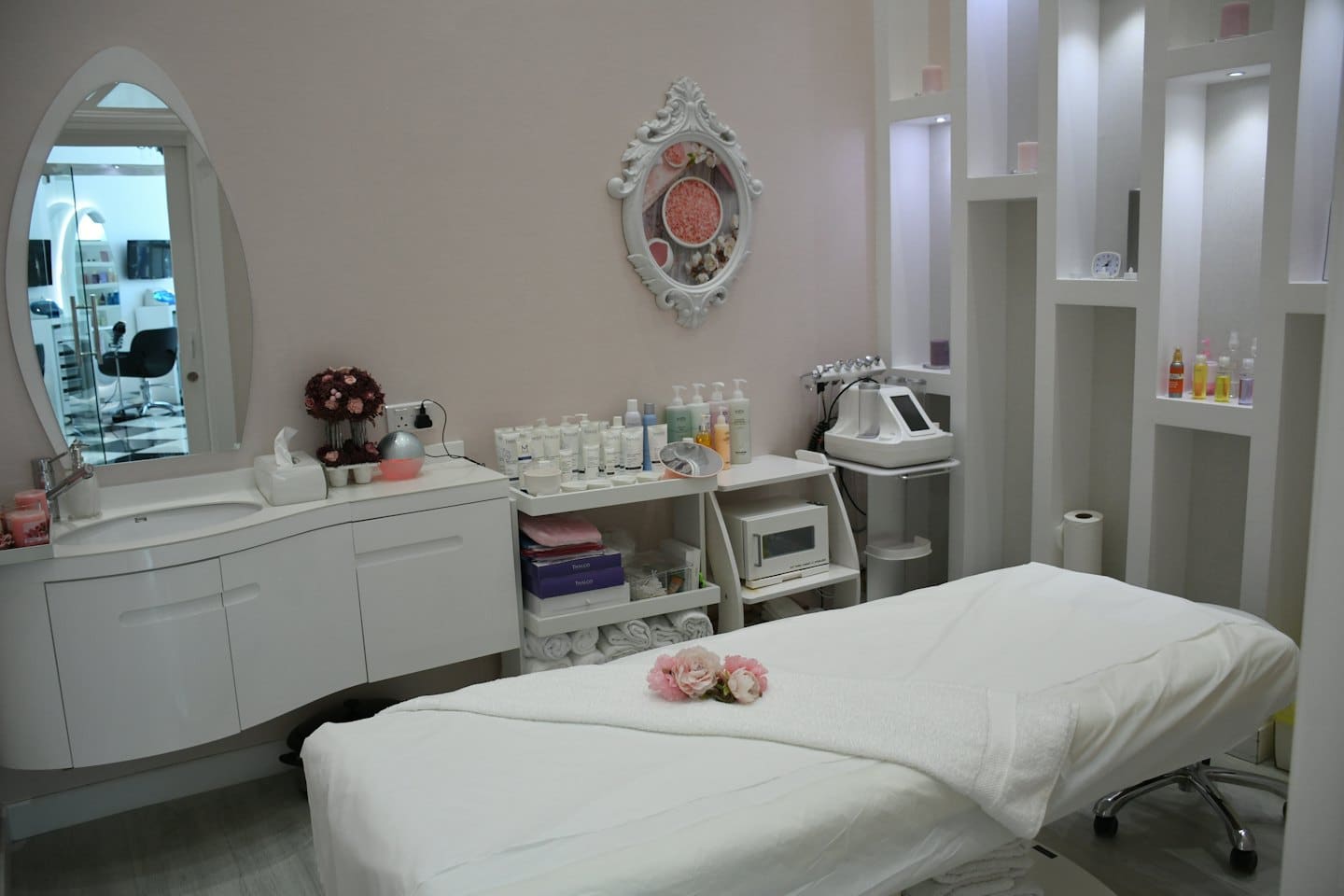 Beyaz yataklı ve pembe çiçekli, temiz güzellik salonu tedavi odası.